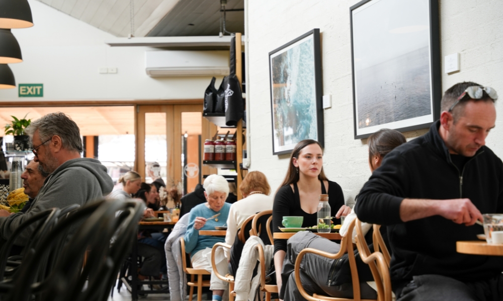 A photo of the inside of The Winey Cow with customers sitting together chatting and enjoying delicious food.