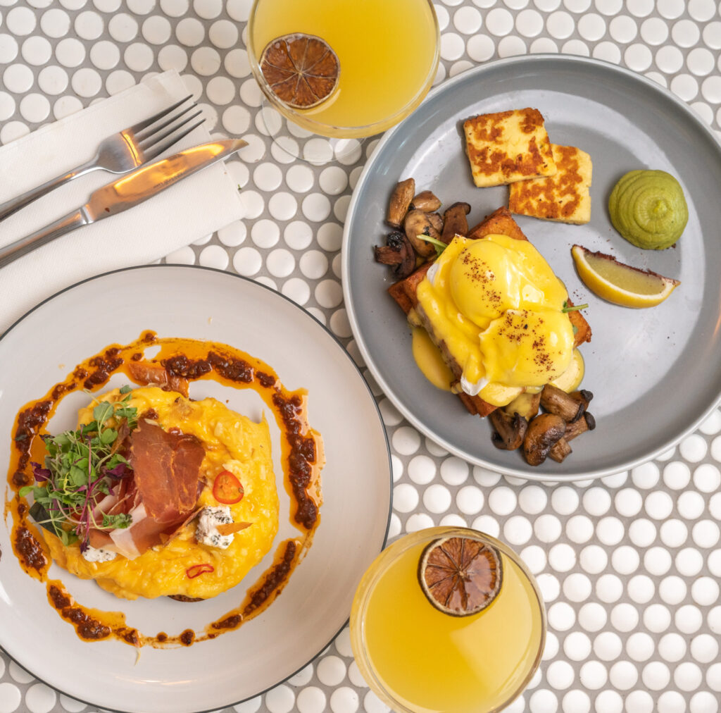 A bird's eye view photo of a Bottomless Brunch, including two delicious breakfast meals with two mimosas.