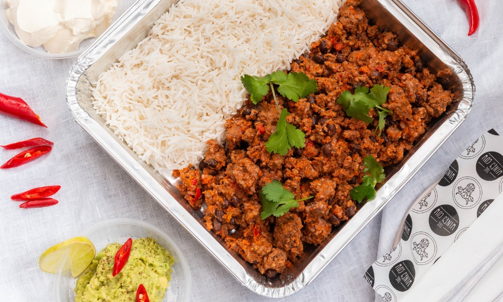 A dish of catering food, with guacamole and chilli served on a table in a bright and light space.