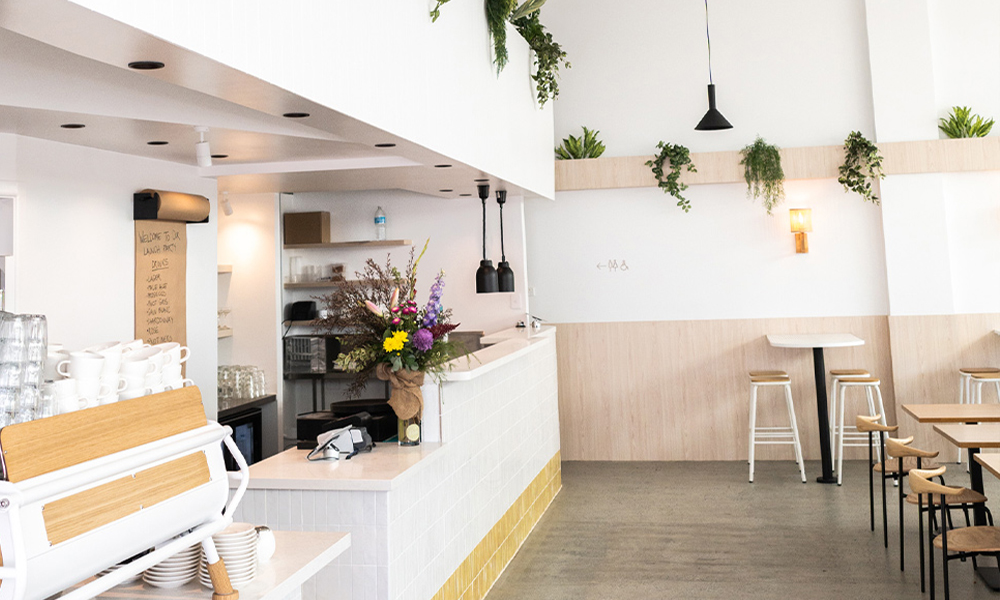 The light and bright interior of The Winey Cow Main Beach location with the front counter, barista station and dining tables.