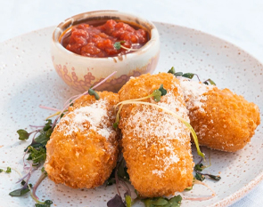 Indulge in The Winey Cow's crispy croquettes, perfectly fried to a golden brown and sprinkled with grated cheese, accompanied by a rich and tangy dipping sauce.