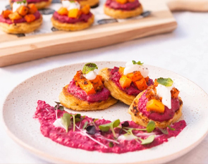 Indulge in our vibrant sweet potato and beetroot canapés, topped with dollops of cream and fresh herbs, creating a visually stunning and delicious starter at The Winey Cow.