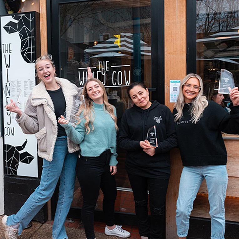 Four The Winey Cow staff girls holding awards from the restaurant industry.