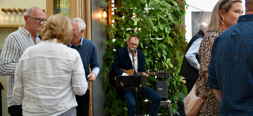 A guitar player playing music on the undercover patio for guests at the event at the Mornington location.