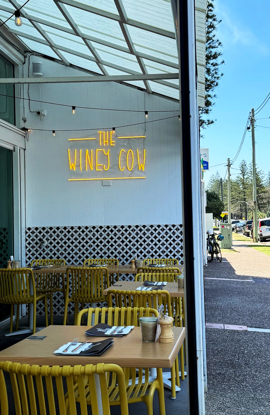The inside of The Winey Cow Main Beach location where there is undercover comfortable seating right by the sidewalk.