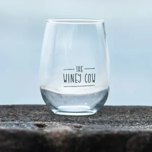 A single clear wine glass with The Winey Cow logo in black.