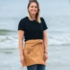 A woman on the beach wearing our tan apron with The Winey Cow logo on the pocket.