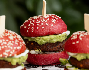 Bright mini fritter sliders with a beetroot bun on a catering tray.